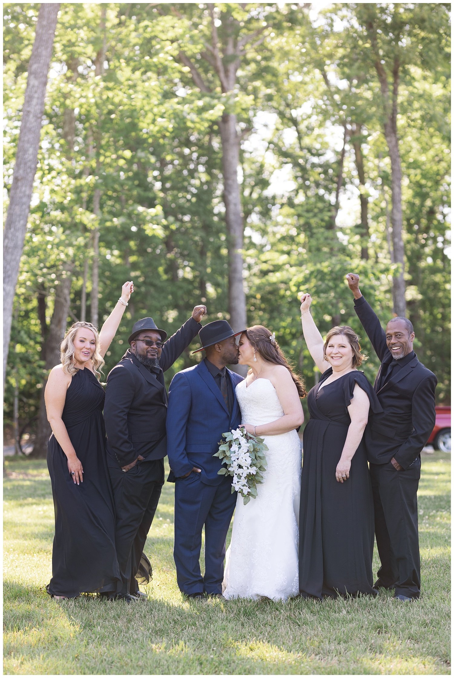 bride and groom kissing while bridal party cheers