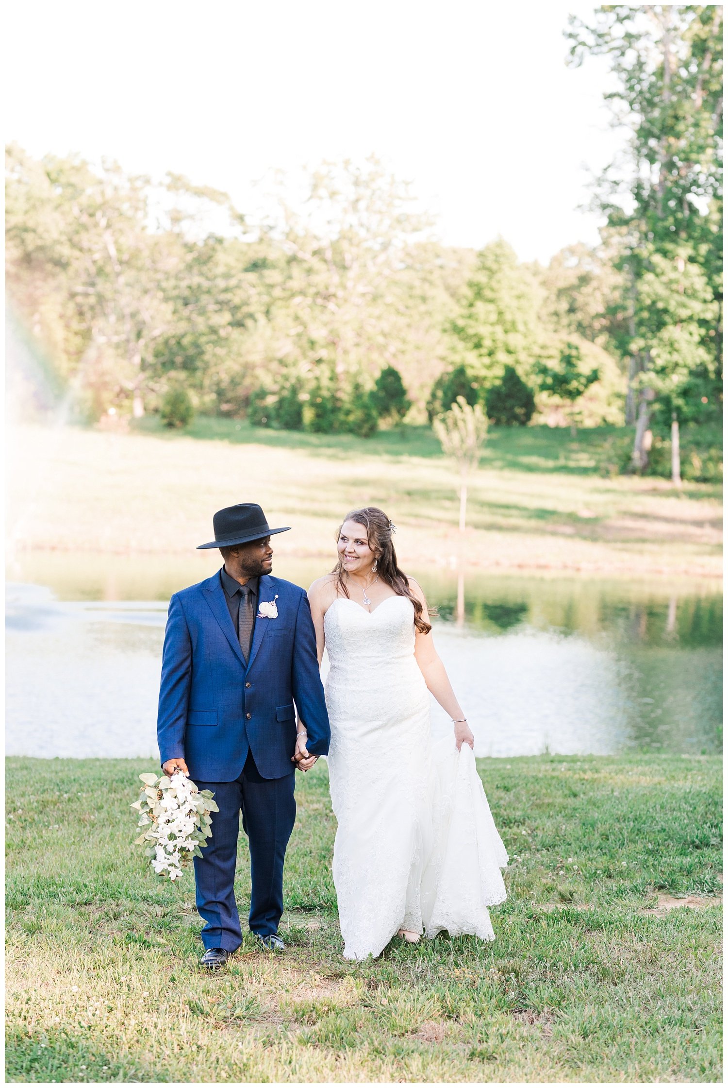 bride and groom walking together at pond 