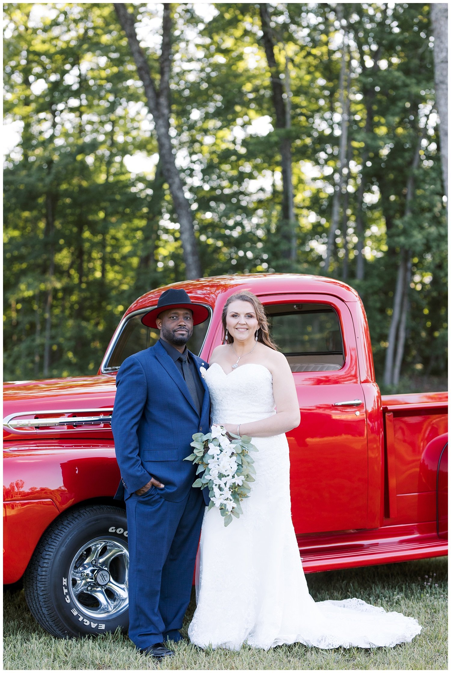 bride and groom posing together in front of red truck
