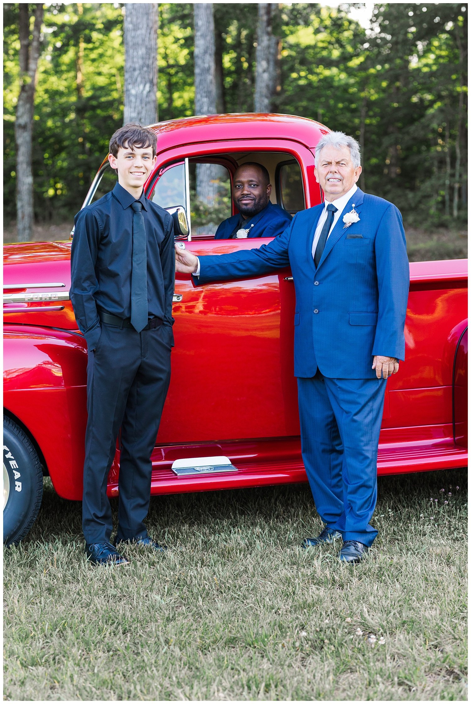 groom and dad posing in front of red truck at wedding