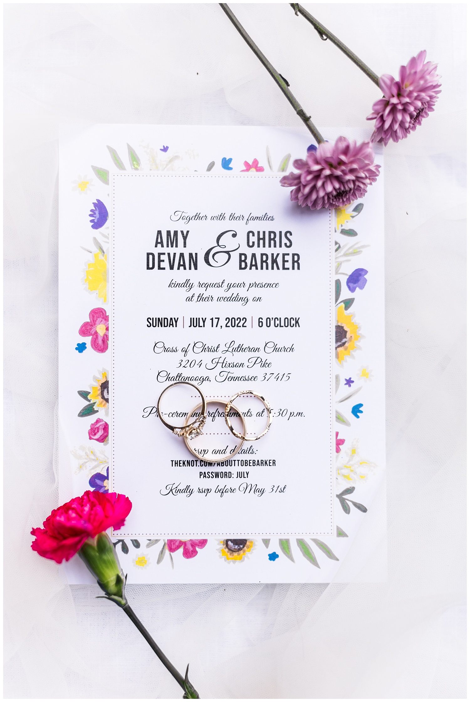 wedding rings and flowers sitting on top of invitation and 