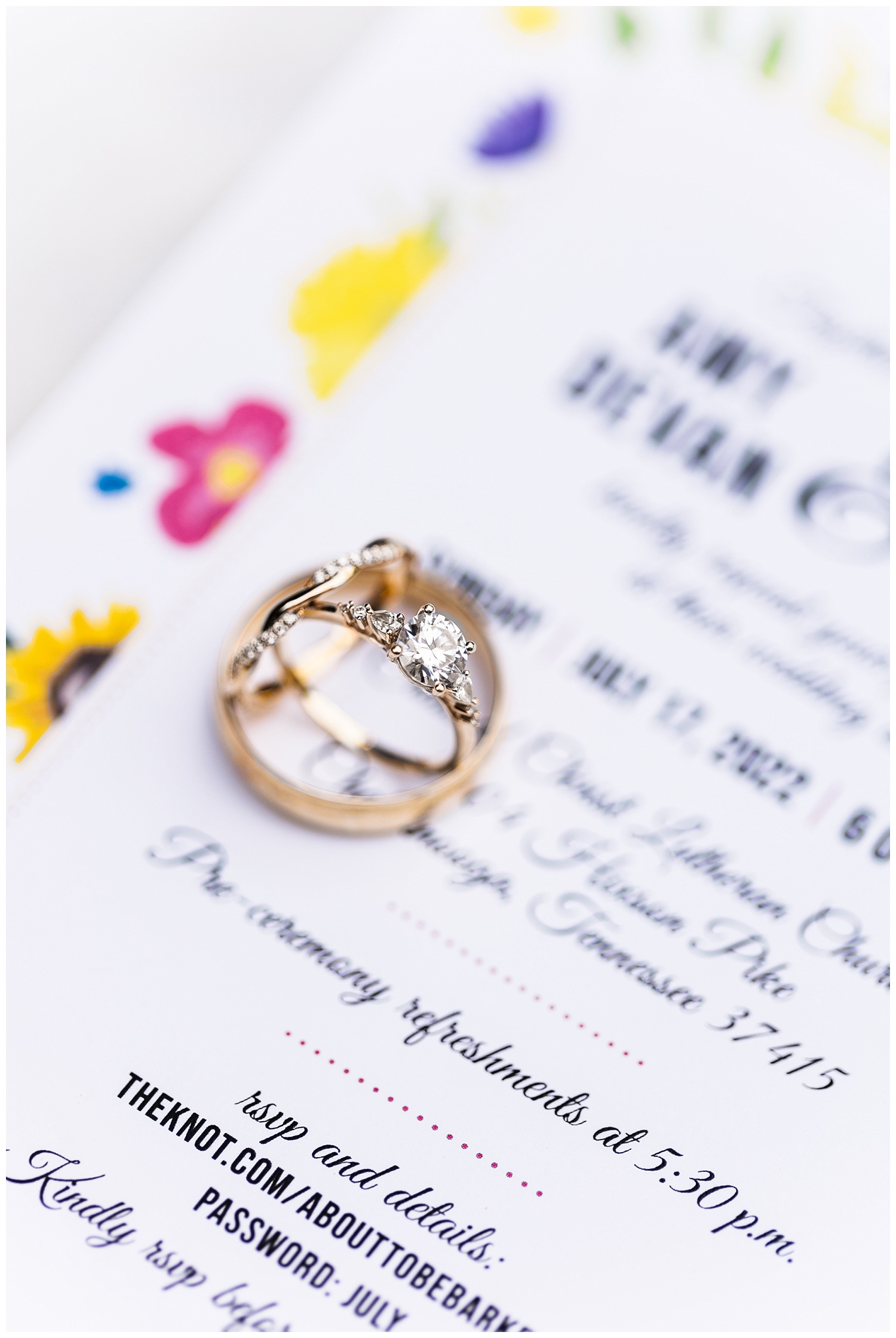 wedding rings sitting stacked on top of invitation