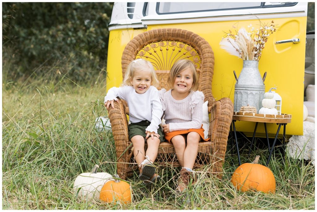 two little girls sitting in a chair at fall mini session