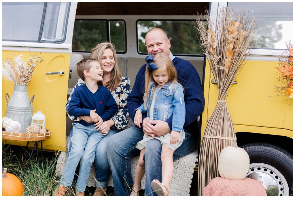 family laughing together sitting on a yellow VW bus for fall mini sessions