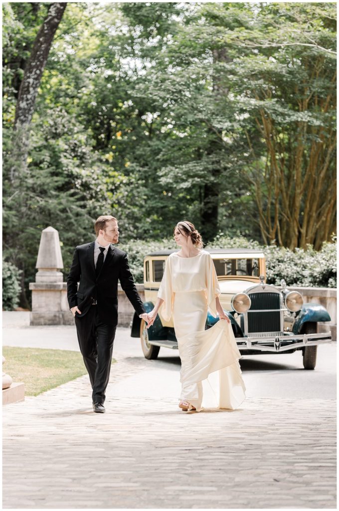 wedding couple walking together in front of an old yellow and green car at the Swan House