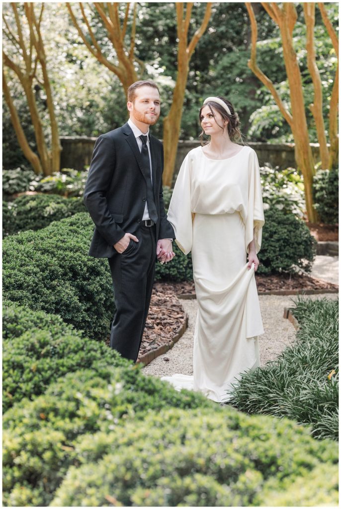 wedding couple holding hands in the Goizueta Gardens at the Swan House