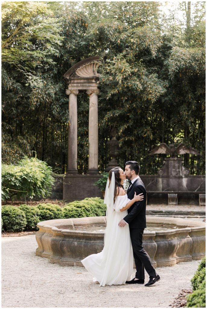 couple kissing in front of the stone fountain at the Goizueta Gardens