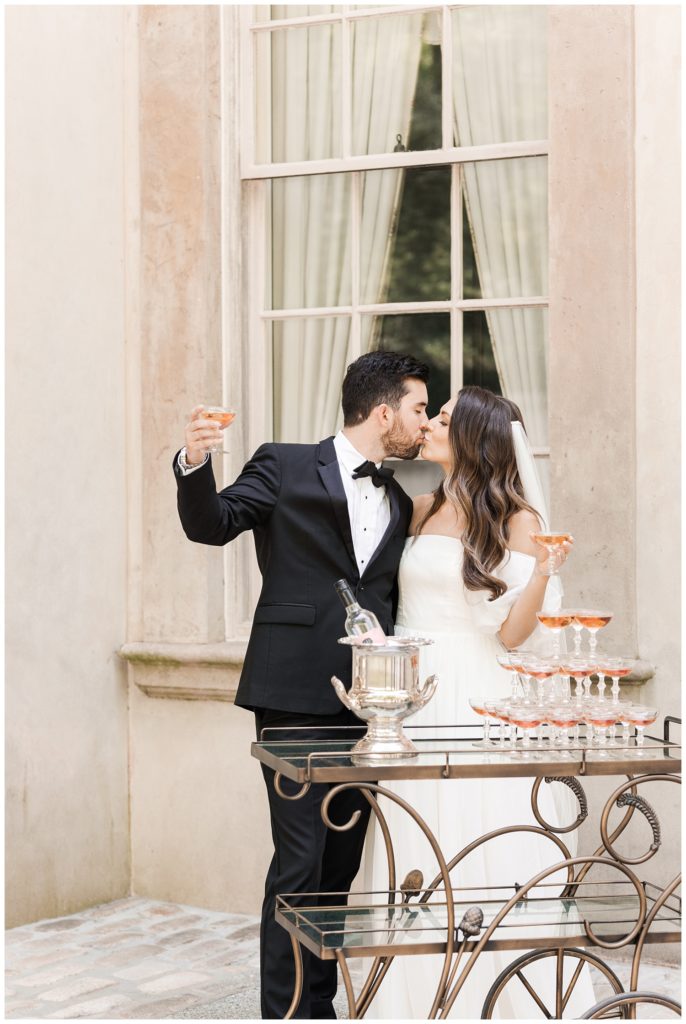 wedding couple kissing and toasting champagne glasses at the Swan House