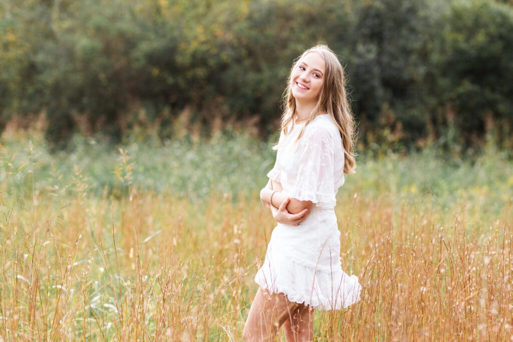 high school senior standing in a field wearing a white dress in Cleveland, TN