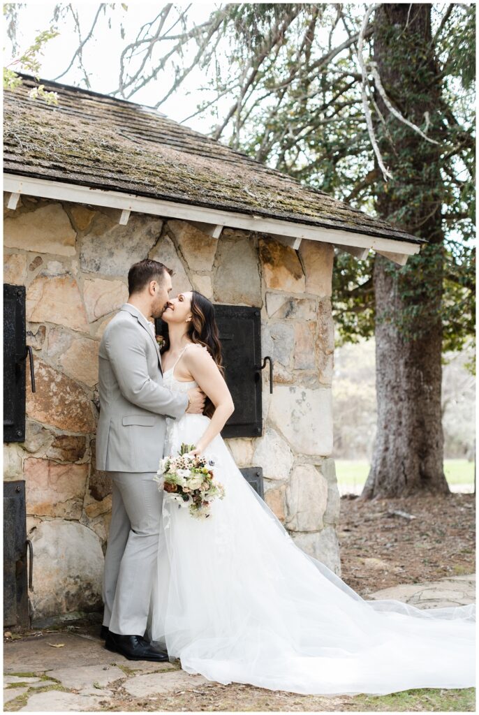 wedding couple holding each other in front of a stone building