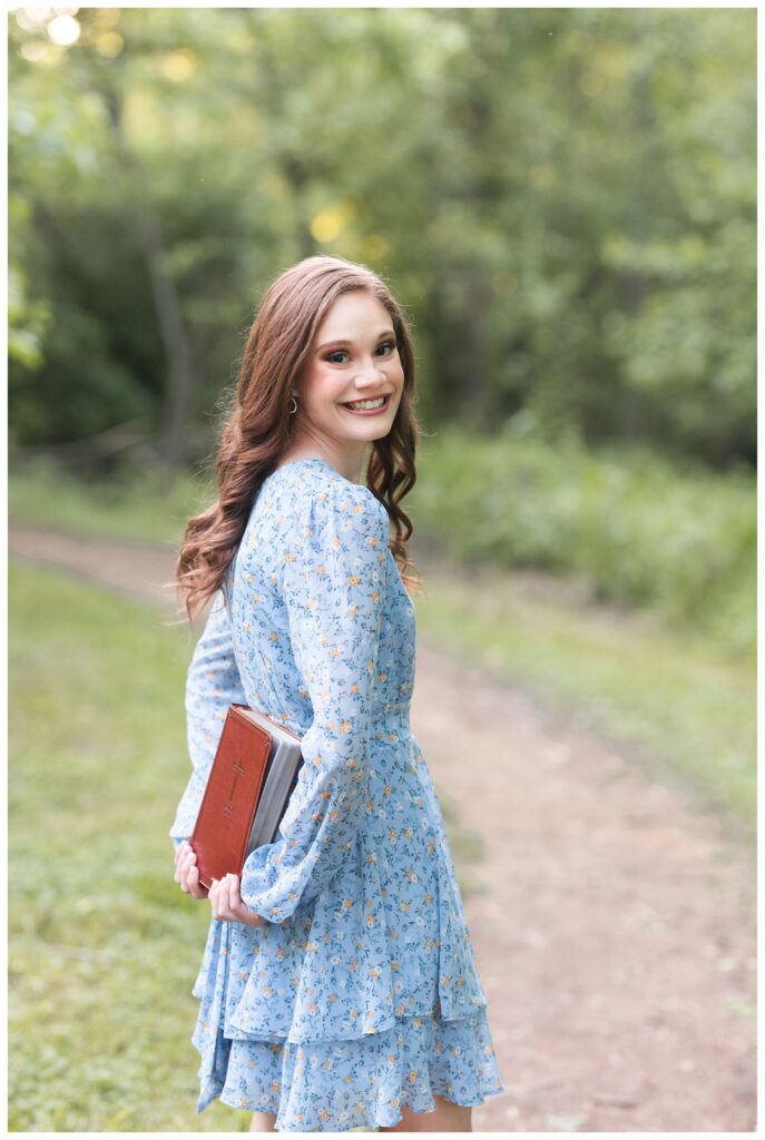 high school senior holding a bible behind her back