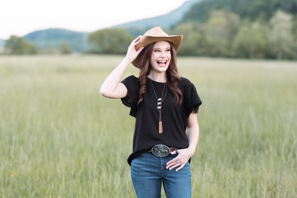 Chattanooga high school senior wearing a cowboy hat and laughing in a field