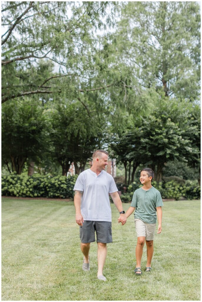 son and dad holding hands and walking on the grass in Cleveland, TN