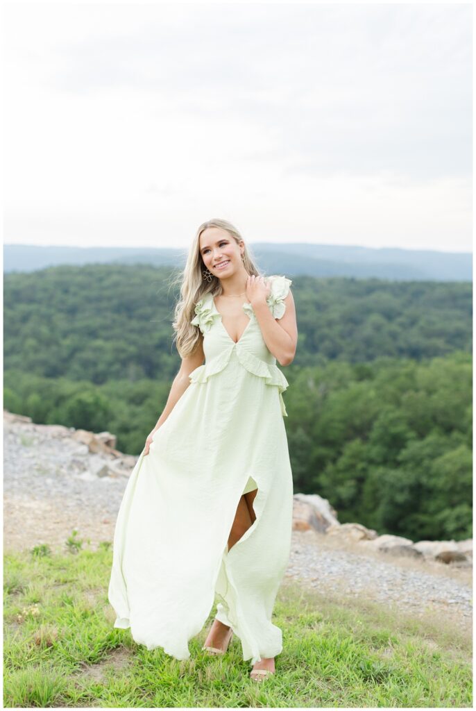 senior wearing a long green dress with the mountains in the background