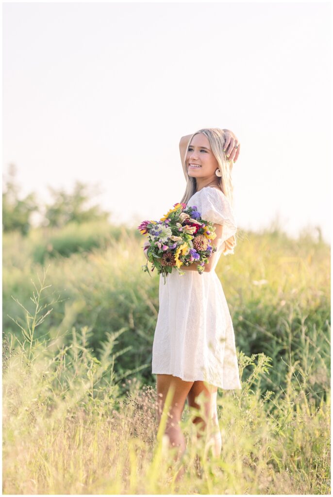 Chattanooga senior holding a bouquet and looking out while standing in a field