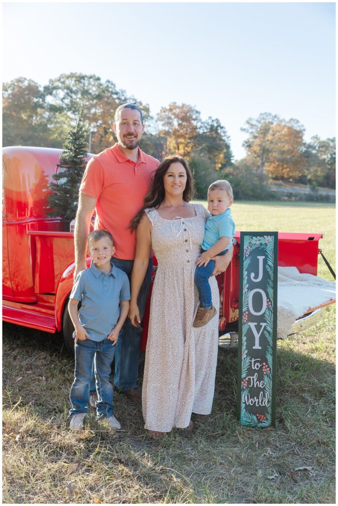 family standing next to a red truck in a field 