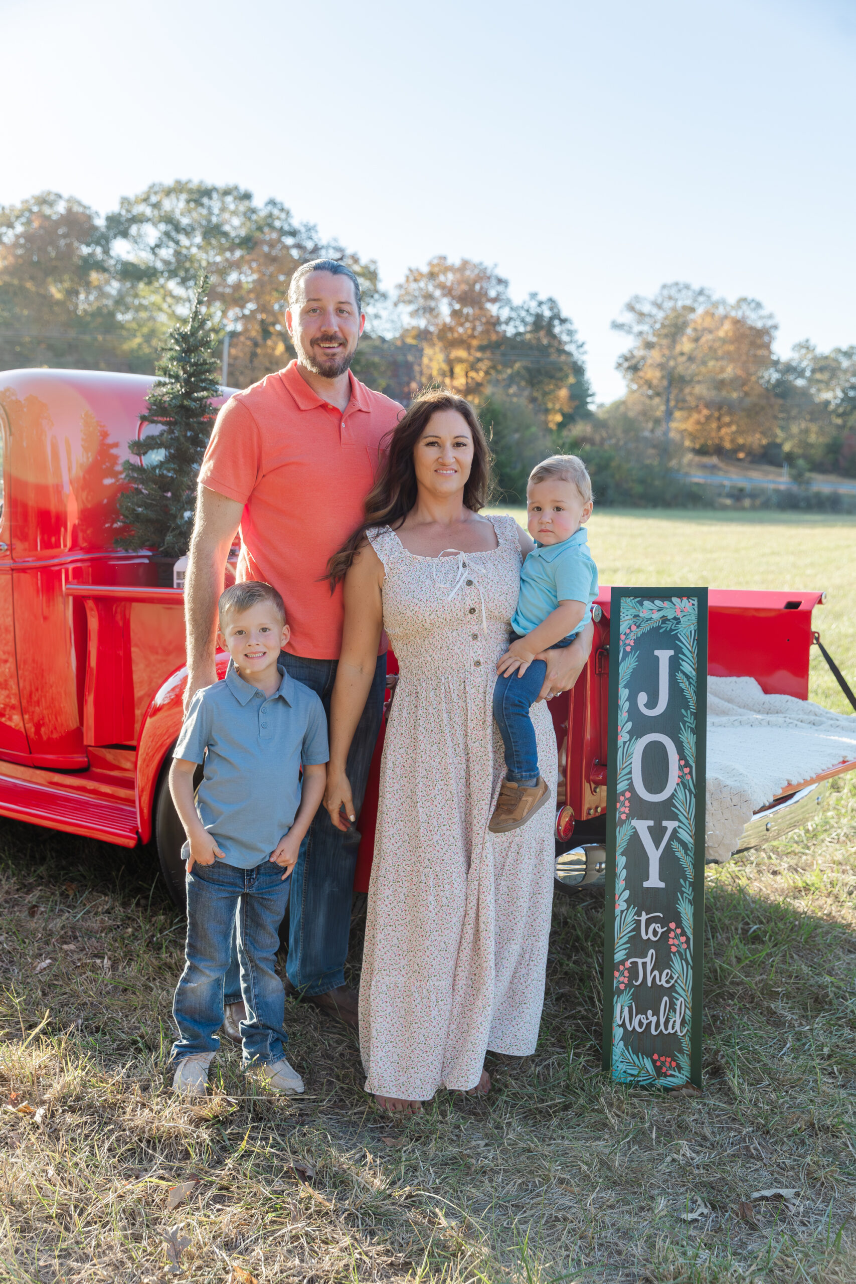 family of four standing in front of a red truck for mini sessions