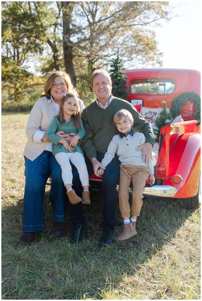 family sitting in the back of a red truck for mini sessions in Chattanooga