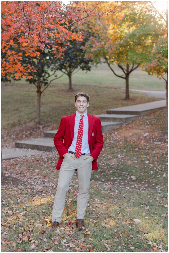 senior posing in front of stairs and fall colored trees at Baylor School