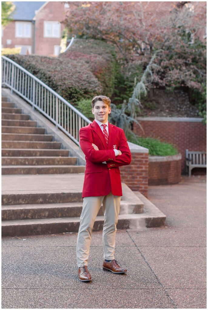 senior guy folding his arms wearing a red jacket in front of a staircase