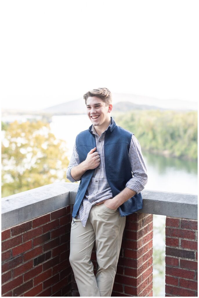 senior boy wearing a button down and blue vest laughing 
