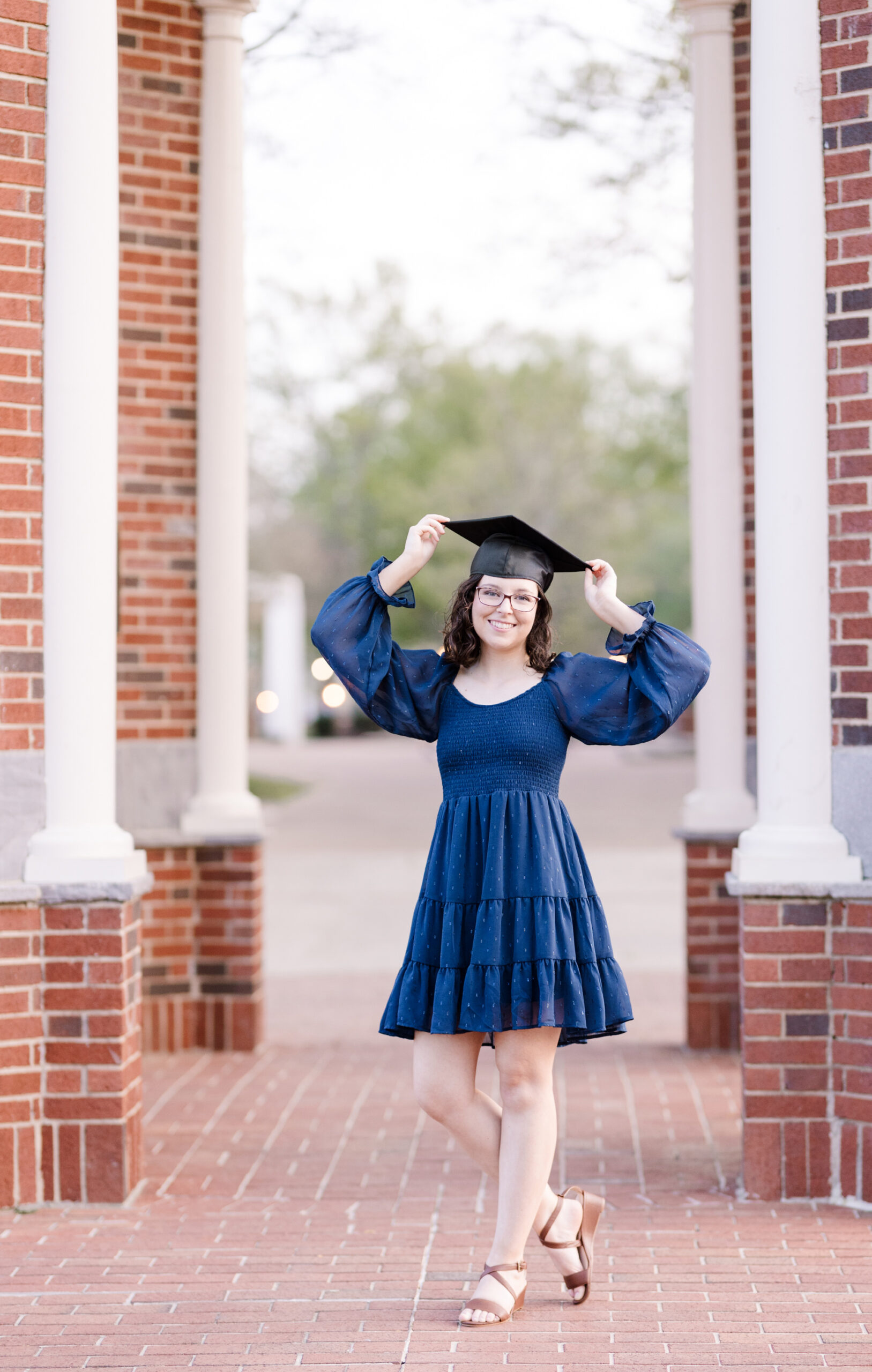 senior holding her cap and wearing a blue dress