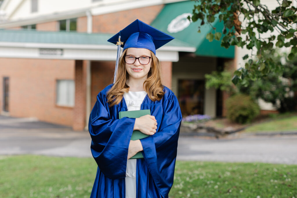 5th grader holding a green book at cap and gown mini session