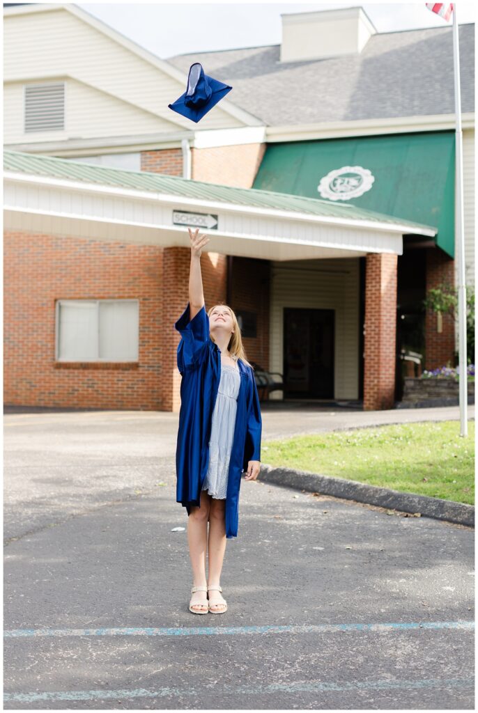 girl wearing a blue dress and throwing her cap in the air at graduation session