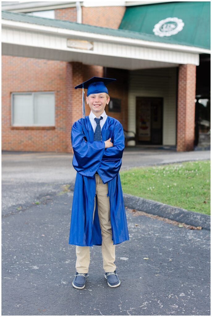 boy crossing his arms while wearing a blue cap and gown at Hickory Valley School