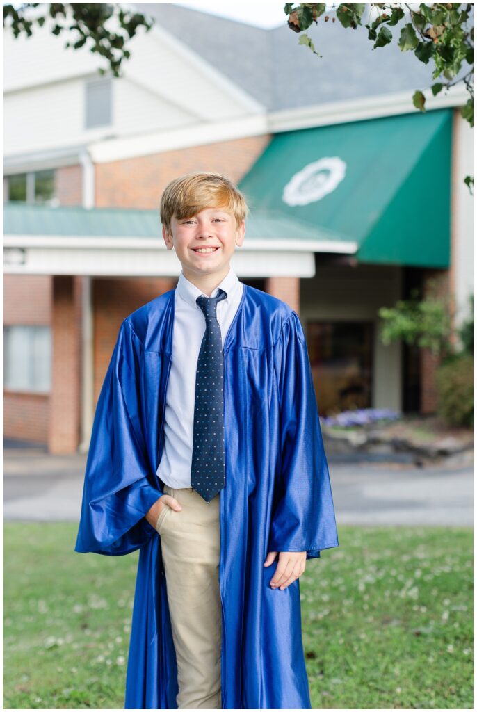 5th grade boy posing with one hand in his pocket and wearing a blue cap and gown