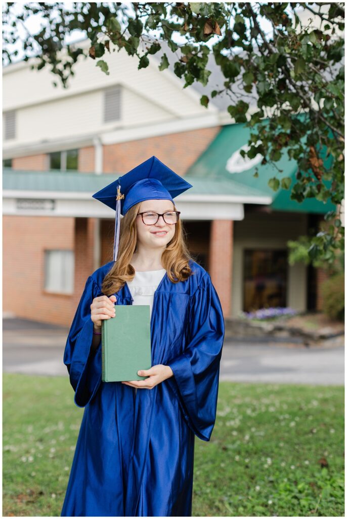 girl holding a book and posing for cap and gown mini session