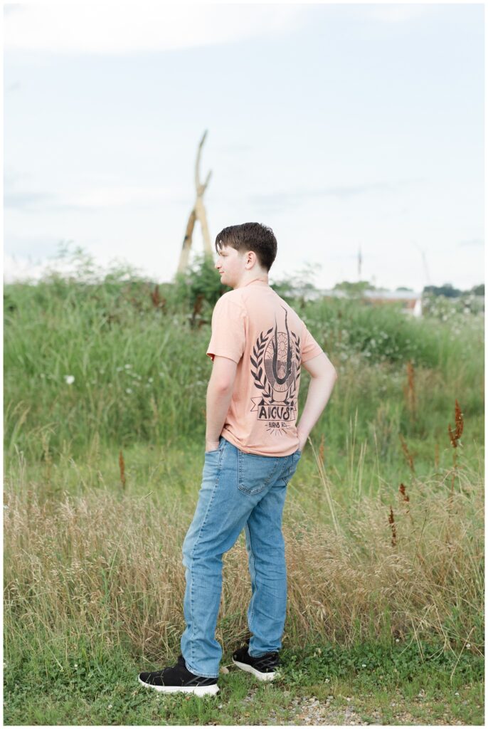 senior boy showing off the back of his t-shirt in a field in Chattanooga