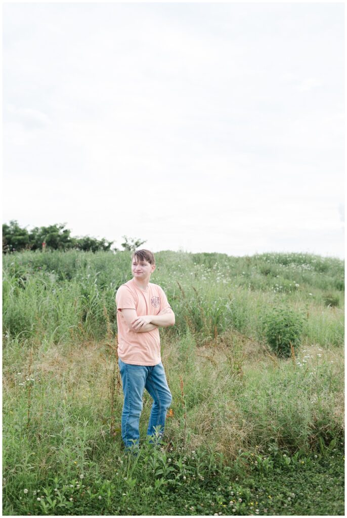 senior boy wearing a shirt and jeans standing in a field in Chattanooga