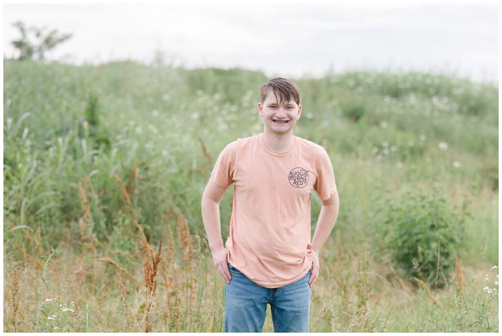 boy posing with hands in his back pockets standing in a field