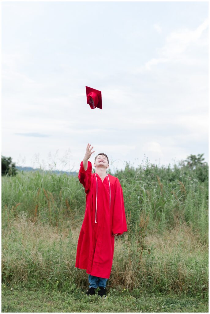 high school senior wearing a graduation gown and throwing his cap in the air