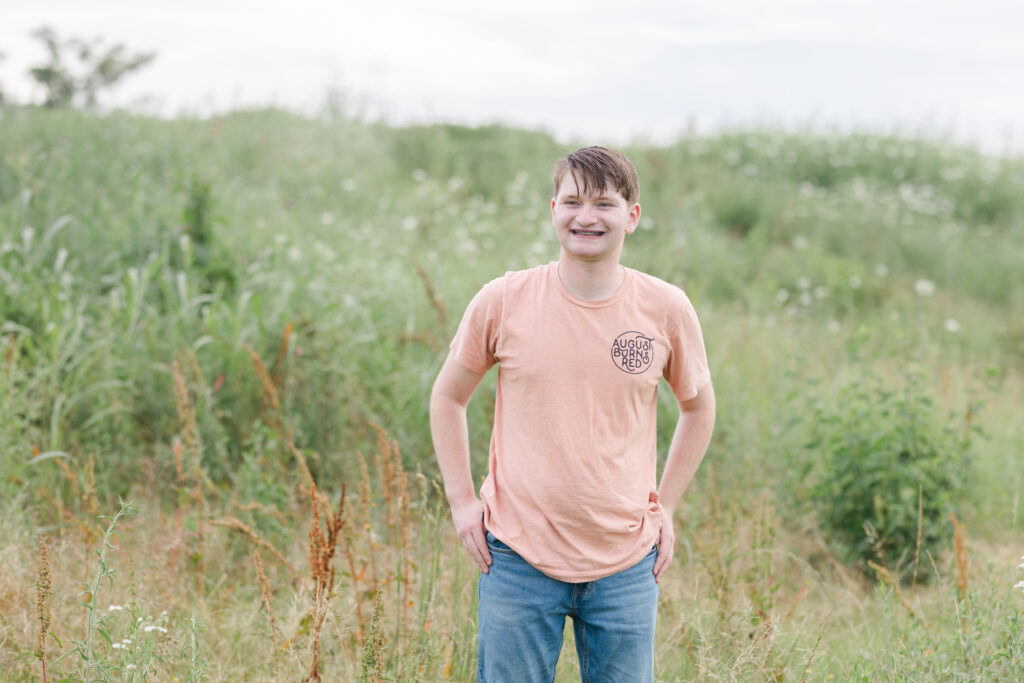 senior boy wearing an orange shirt and jeans at Chattanooga session