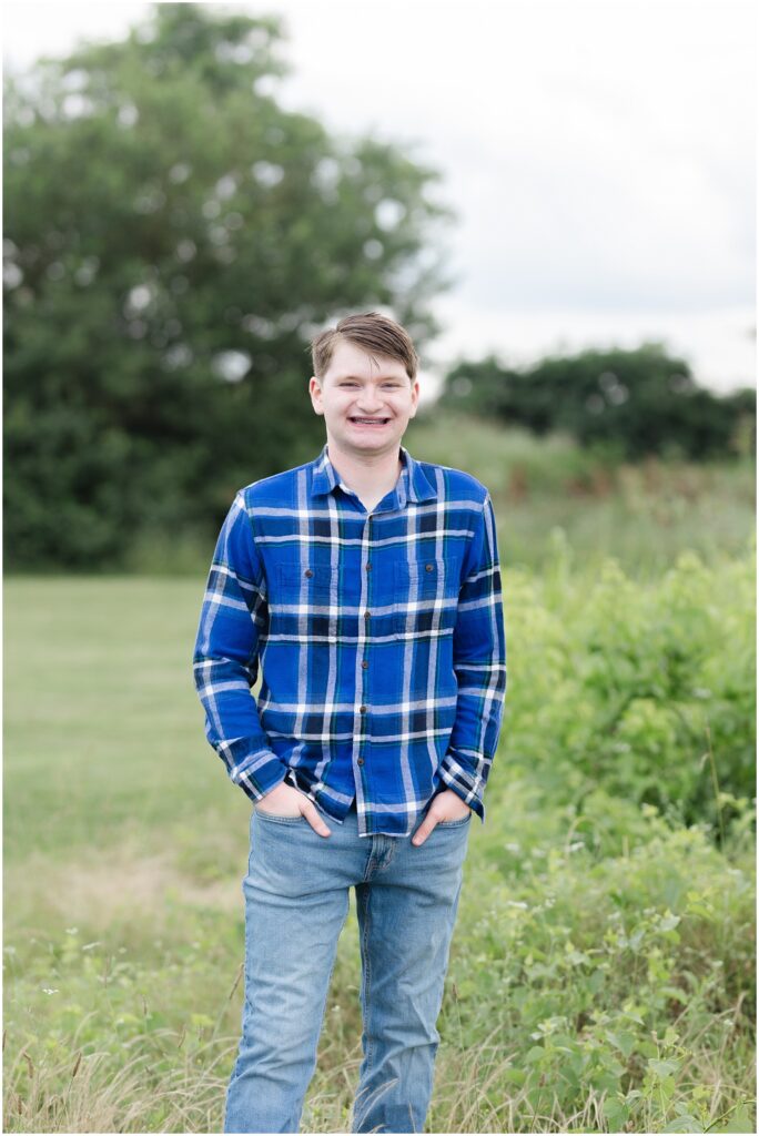 senior boy posing next to some plants at the Sculpture Fields