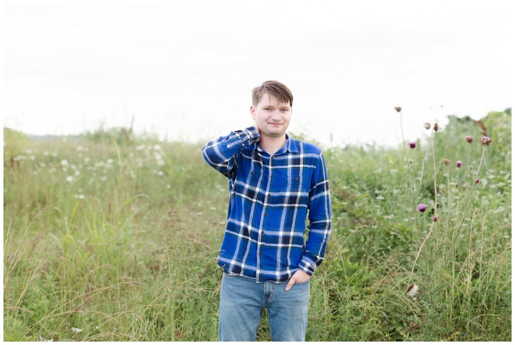 senior boy posing in the grass at the Sculpture Fields