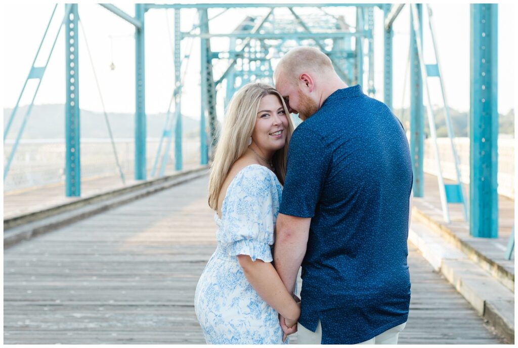 girl smiling and holding hands with her fiance on the bridge in Chattanooga