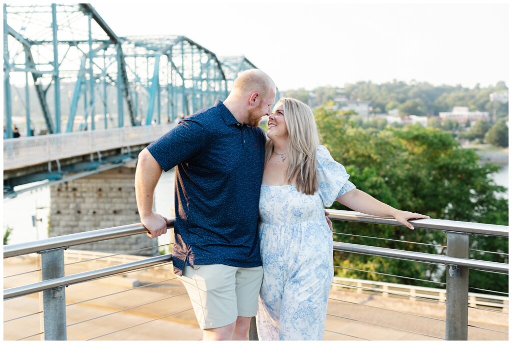 engaged couple leaning against a steel railing in downtown Chattanooga