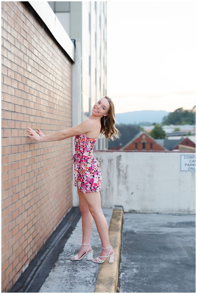 senior girl posing against a brick wall on top of a parking garage in Chattanooga