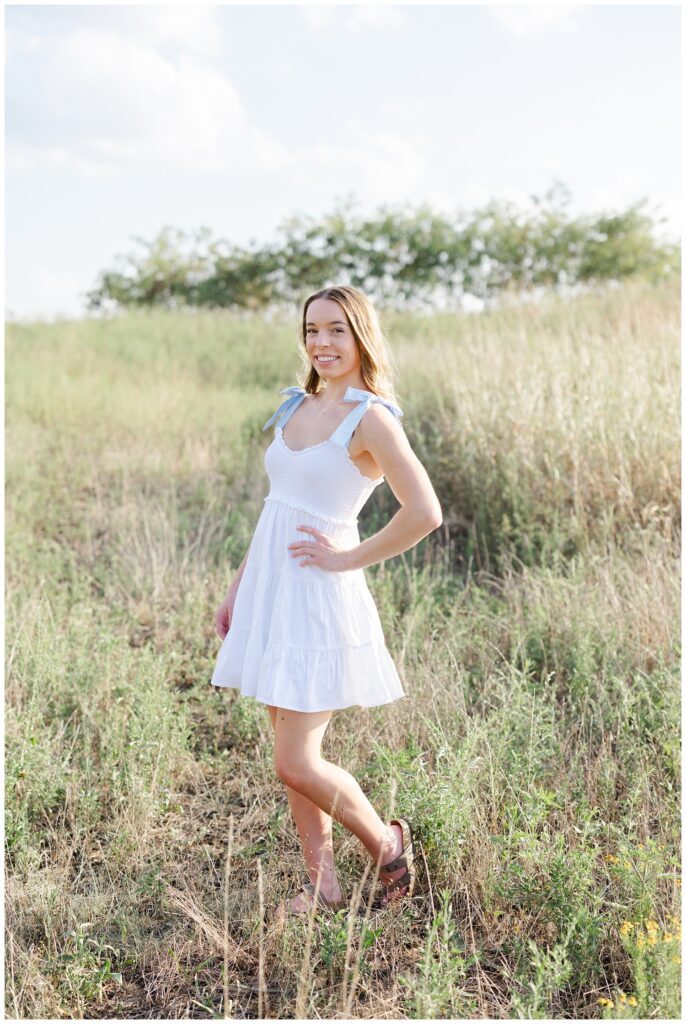 high school senior posing in a field wearing a white dress in Chattanooga