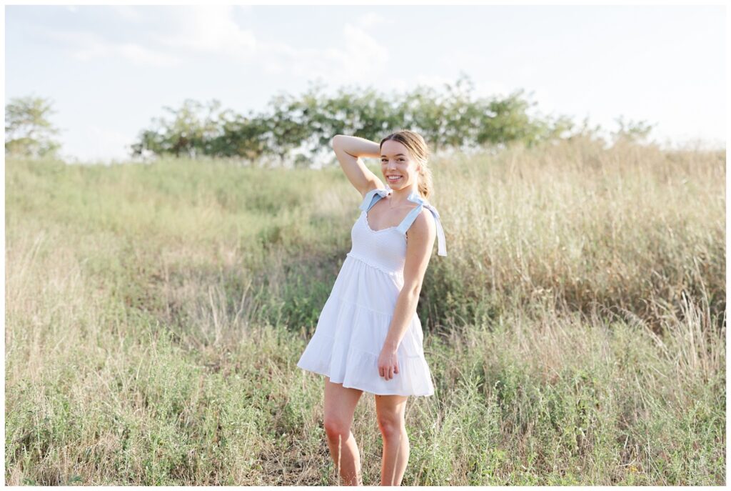 high school senior posing in a field wearing a white dress at Sculpture Fields