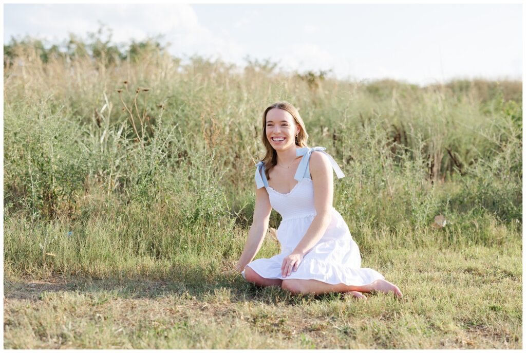 high school senior girl sitting and laughing at the Sculpture fields near downtown Chattanooga