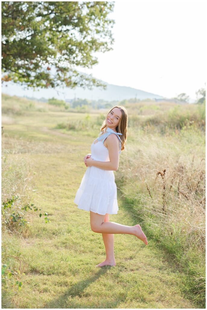 senior girl kicking her leg back in the grass at Sculpture Fields