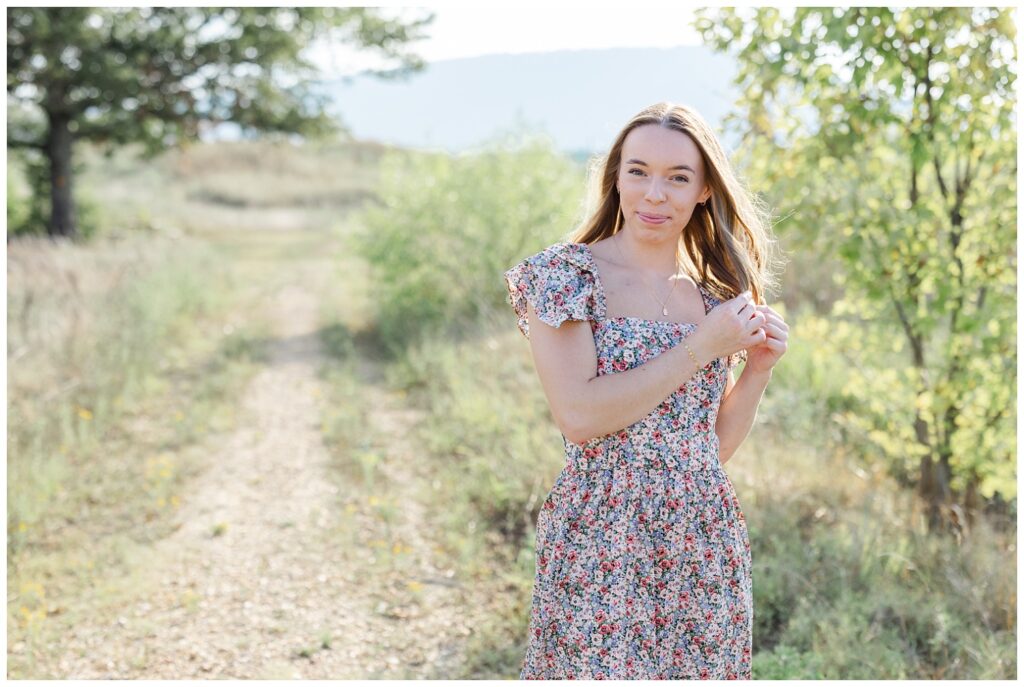 high school senior holding her hair on a trail at Sculpture Fields