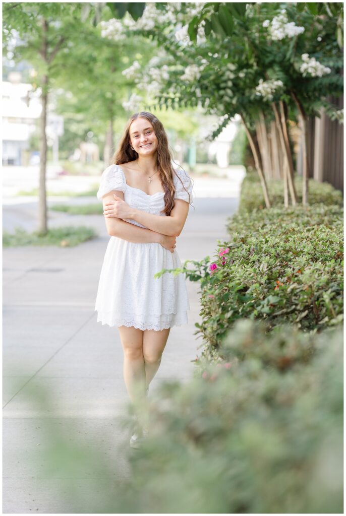 high school senior crossing her arms while posing on a sidewalk