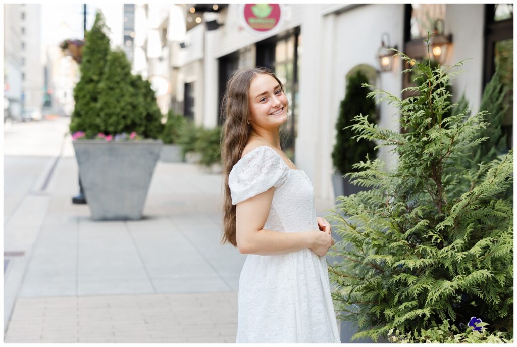 girl looking back while holding her hands at her waist during senior session