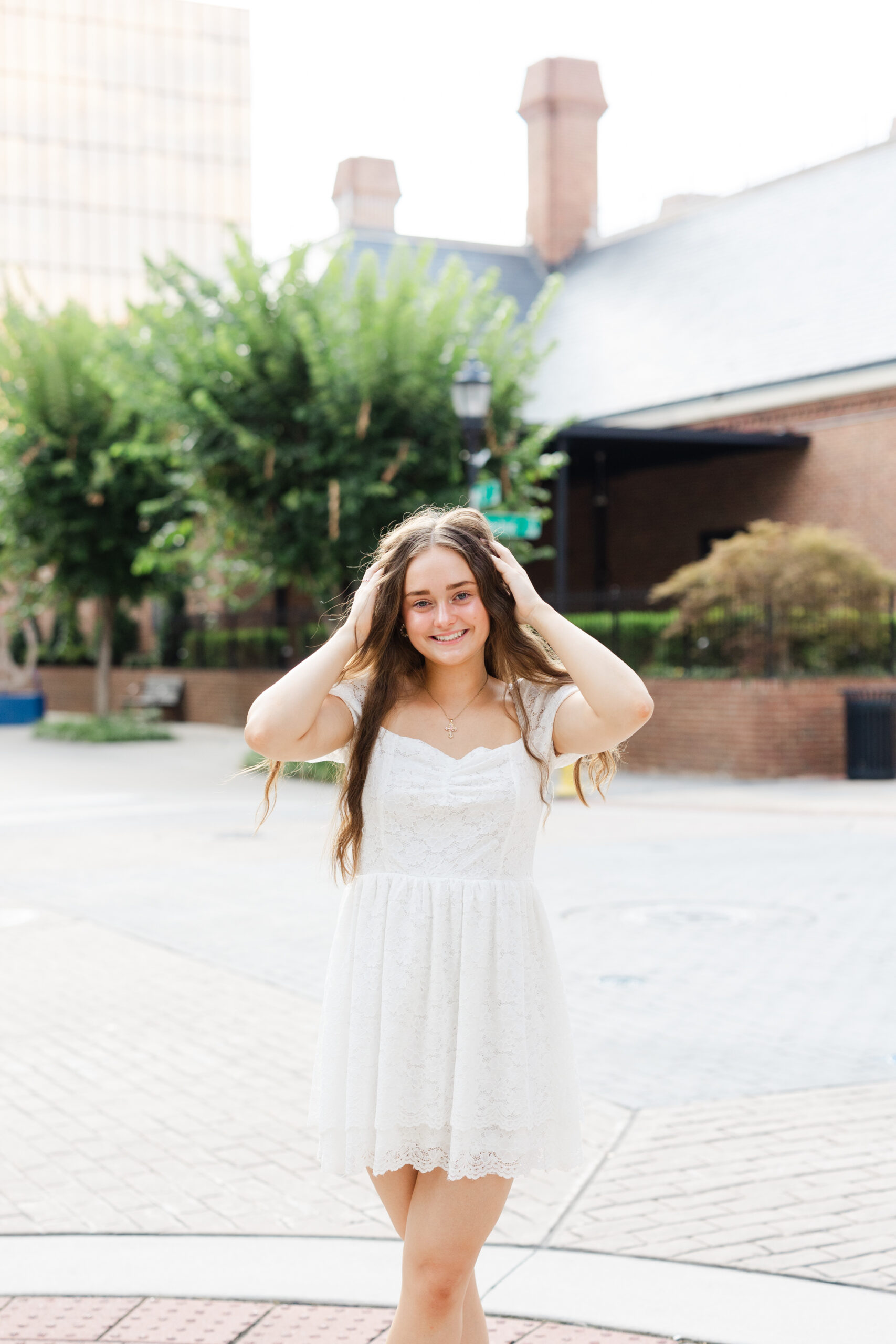 girl with hands in her hair posing on the curb