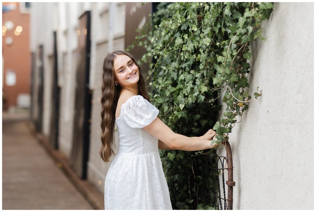 girl posing next to a wall covered with ivy at umbrella alley